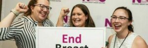 Three smiling NBCC staff members holding a sign that reads End Breast Cancer at the 2023 Advocate Leadership Summit