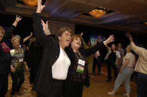 Dr Susan Love dancing with arms in the air at a National Breast Cancer Coalition meeting