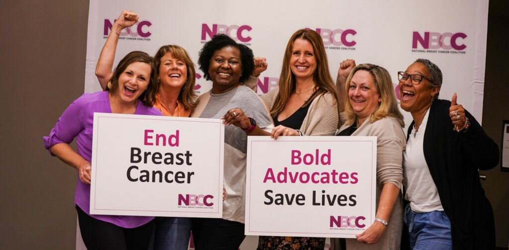 Six smiling and laughing women stand in front of an NBCC backdrop holding signs that say End Breast Cancer and Bold Advocates Save Lives