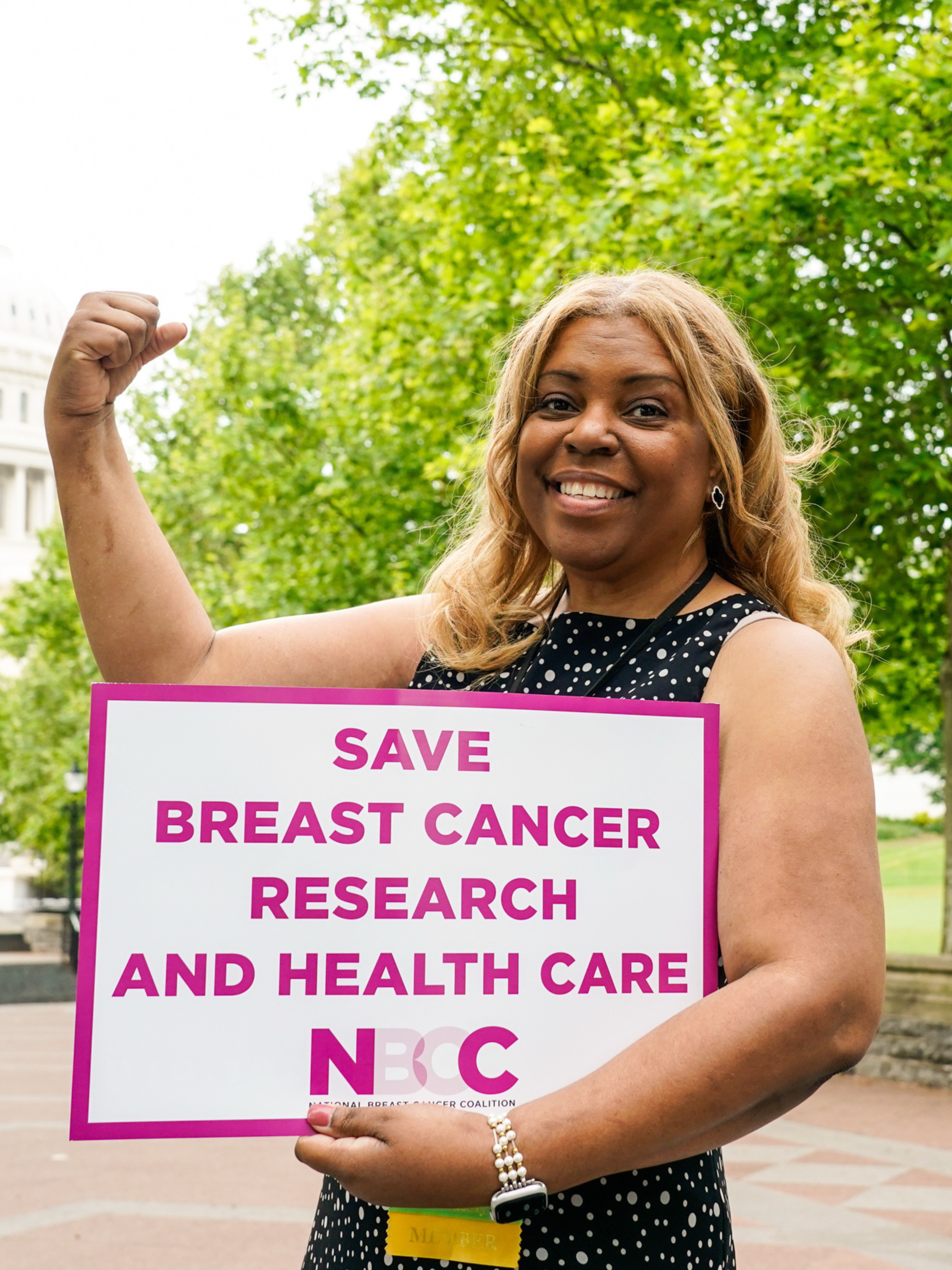 nbcc member on capitol hill holding a sign reading save breast cancer research and health care