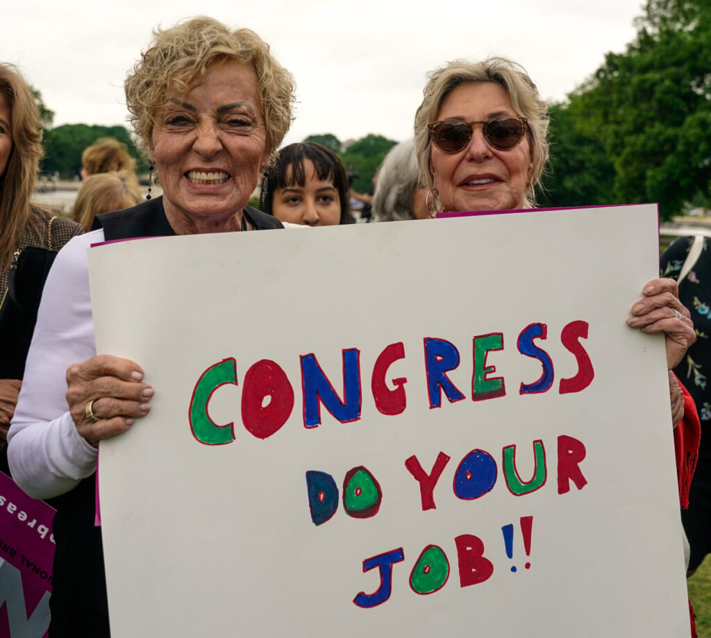 Women holding sign that reads Congress do your job